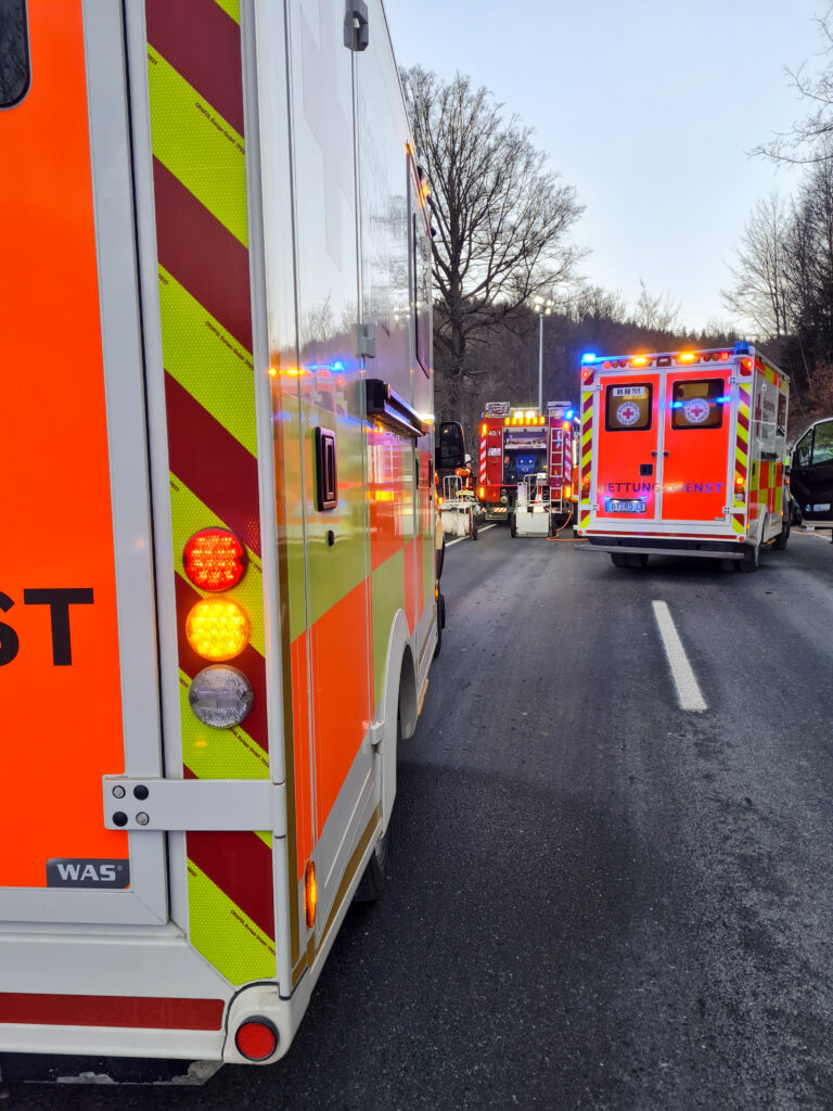 Einsatzkräfte des BRKs am Einsatzort auf der B 303 mit Blaulicht.