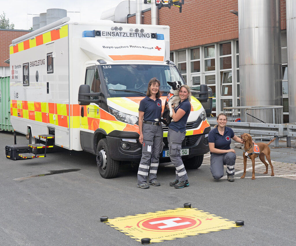 Hundeführerinnen der BRK-Rettungshundestaffel Bayreuth vor dem Einsatzleitwagen der UG San EL Stadt und Landkreis Bayreuth.