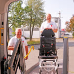 Schulungstag des BRK-Patientenfahrdienst Bayreuth - Mitarbeitende des BRK-Patientenfahrdienstes und ein Tragestuhl nutzen die Hebevorrichtung eines Spezial-Fahrzeuges des BRK-Patientefahrdienstes.