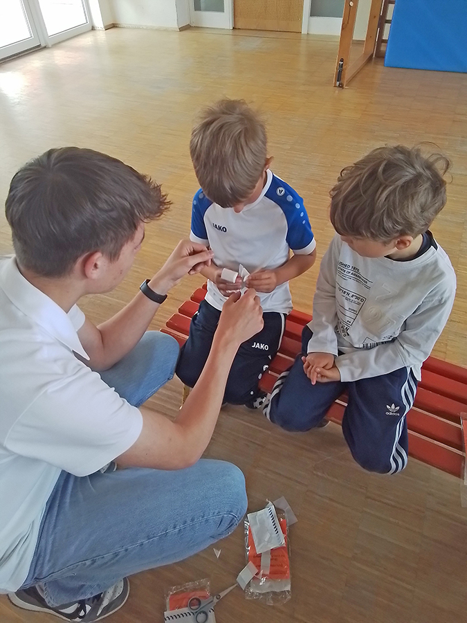 Kindergartenkinder erlenen Maßnahmen der Ersten Hilfe.