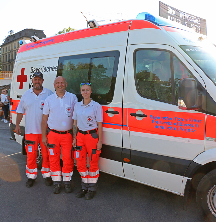 Das Bild zeigt einen Notfallkrankenwagen der BRK Bereitschaft Pegnitz im EInsatz zur Absicherung des Paul Kalkbrenner-Open-Air-Konzertes in Bayreuth und seine dreiköpfige Besatzung.