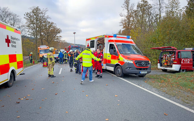 Einsatzkräfte am Einsatzort auf der B22. Zu sehen sind Rettungswagen des bayerishen Roten Kreuzes, Einsatzfahrzeuge der Feuerwehr sowie Einsatzkräfte von BRK, einem privaten Rettungsdienstleister und der DRF-Luftrettung.