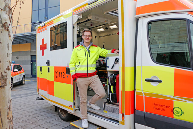 Daniel Schott vom Arbeitskreis Rettungsdienst mit einem Rettungstransportwagen bei der Fahrzeugschau des Tag des Ehrenamtes 2024 am Rotmain-Center Bayreuth.