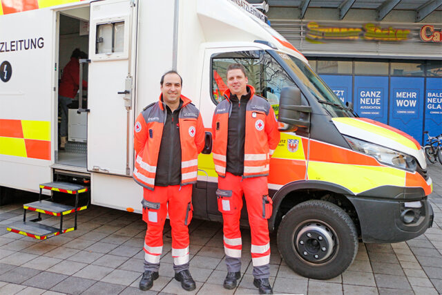 Mischa Nietfeld und Patrick Czekalla von der UG-SanEL beim Tag des Ehrenamtes 2024 bei der Fahrzeugschau am Rotmain-Center Bayreuth. Im Hintergrund der ELW.