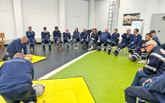 Mitarbeiter des BRK-Patientenfahrdienstes beim Training der Maßnahmen der Reanimation vor dem versammelten Team des BRK-Patientenfahrdienstes.